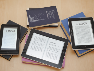 Tablet readers stacked on books with screen showing "E-book"; link to ebooks page