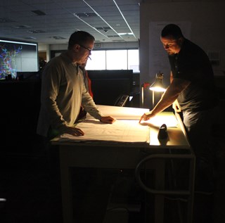 Lakeland Electric staff looking over work at a table in a dark room