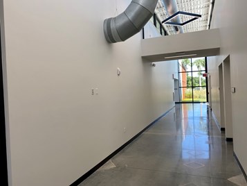Hallway at Lake Crago Outdoor Reacreation Complex heading towards classrooms. Glass windows at the far end look out to Crago FL native landscaping