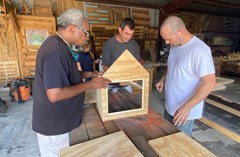 Two workshop attendees hold their little library together as one prepares the drill.