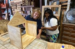 Two workshop attendees smiling at the camera as they hold their little library together as the glue dries.