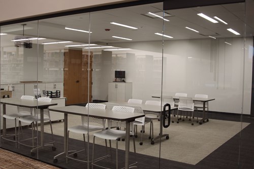 Lakeland History Room looking through glass window wall at tables and chairs