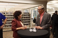 Two people conversing around tall table with library bookshelves in background at Lakeland History and Culture Center reception