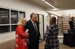 Three people conversing together near seating during the Lakeland History and Culture Center reception with library bookshelves in the background