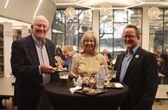 Three people standing around tall table with food at Lakeland History and Culture Center reception