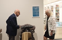 Man and woman looking at saddle on display in Lakeland History and Culture Center exhibit in front of poster with text "Spanish American War McClellan Saddle"