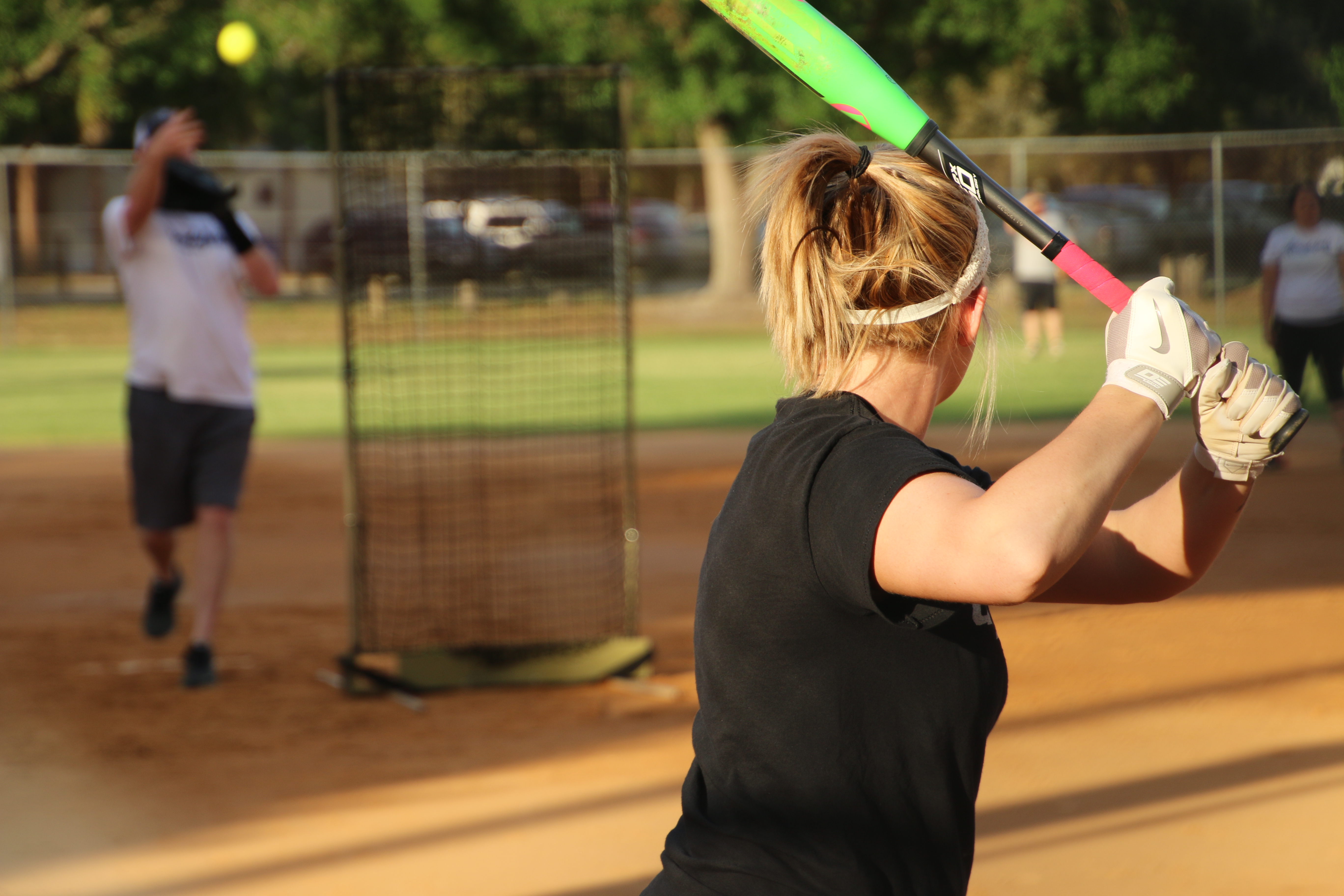 Softball field at Sunset, woman in the foreground with a bat about to swing