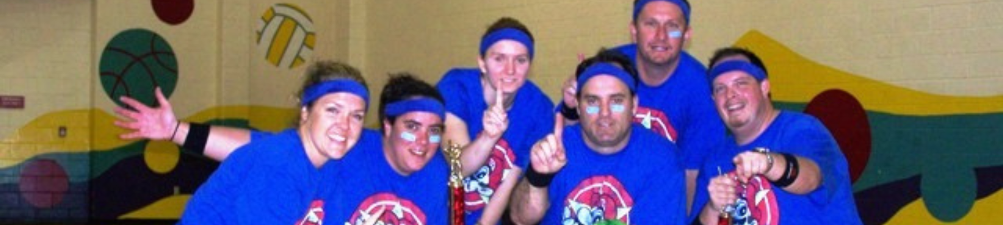Throwback picture of dodgeball league at Kelly Rec in the gym, Group in matching tshirt making #1 sign with their hands