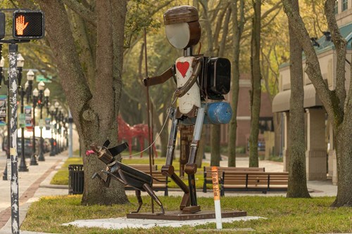 Picture of a robot man with a red heart on his chest out backpacking with his dog.