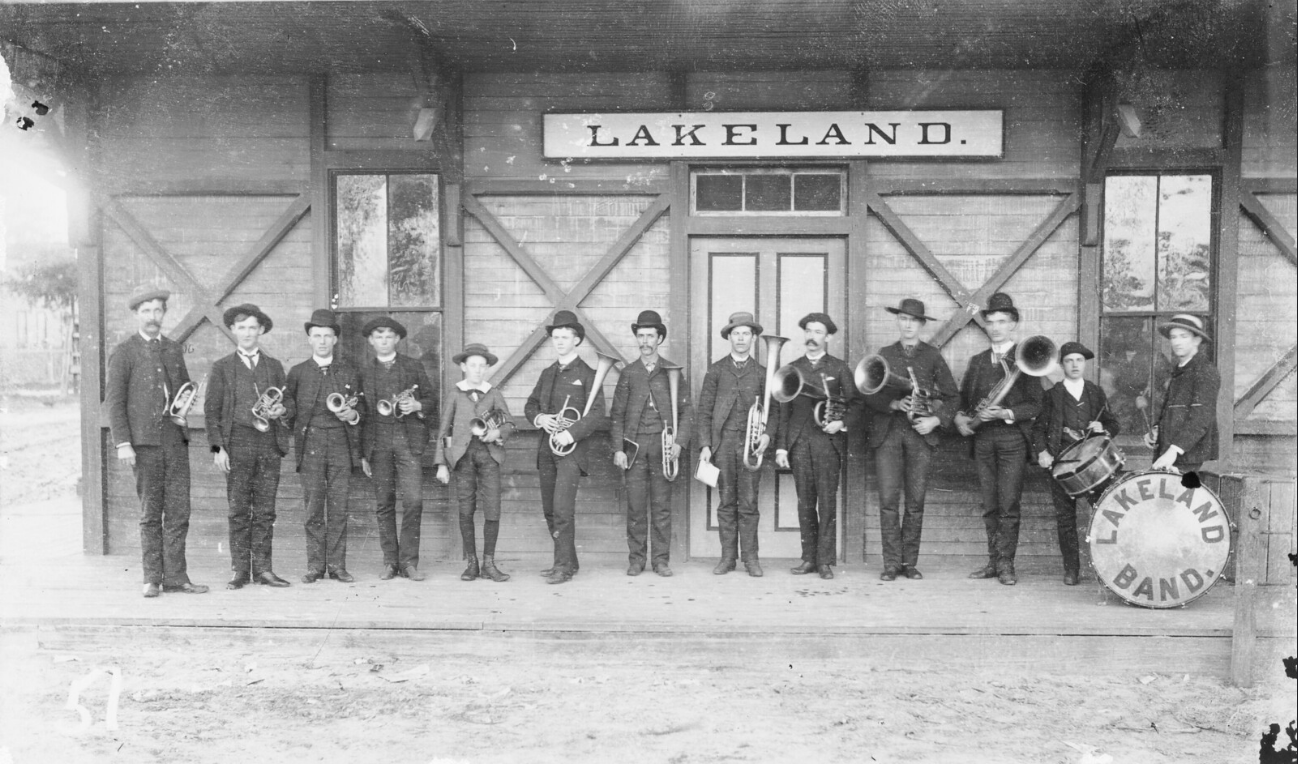Members of the Lakeland Brass band wait at the train station in Lakeland, Florida to greet the train carrying President Grover Cleveland, 1895; link to Flickr "Sounds of Music" album