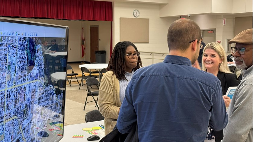 A picture of a group of four people next to a large screen with a map of Memorial Blvd.