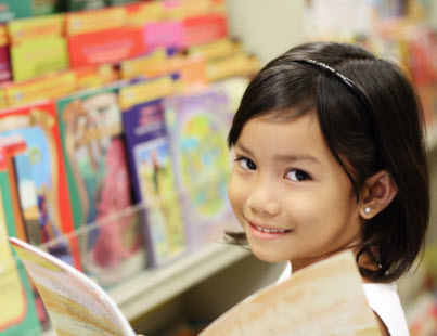 Girl reading a book in front of a display of books