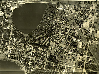 Aerial photograph of Lakeland in 1925 showing the entirety of Lake Mirror and surrounding land.  At this time the Lake Mirror Promenade is not yet built, but an abundance of citrus is also visible.; link to contentDM "Underwood Aerial Photographs" collection