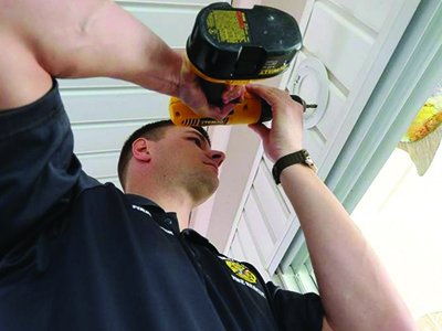 A photo of a firefighter installing a smoke alarm
