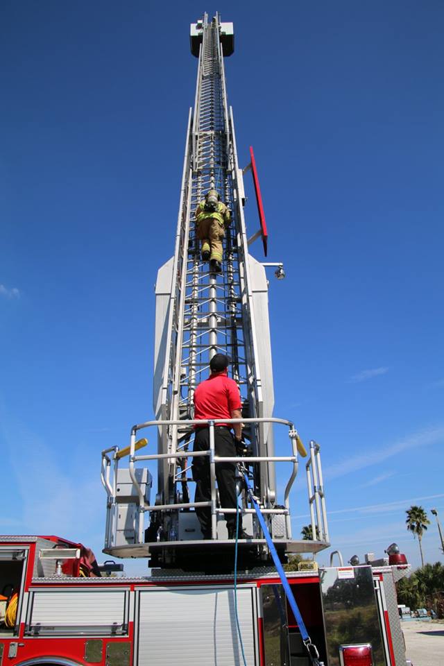 A picture of a firefighter climbing the fire trucks ladder