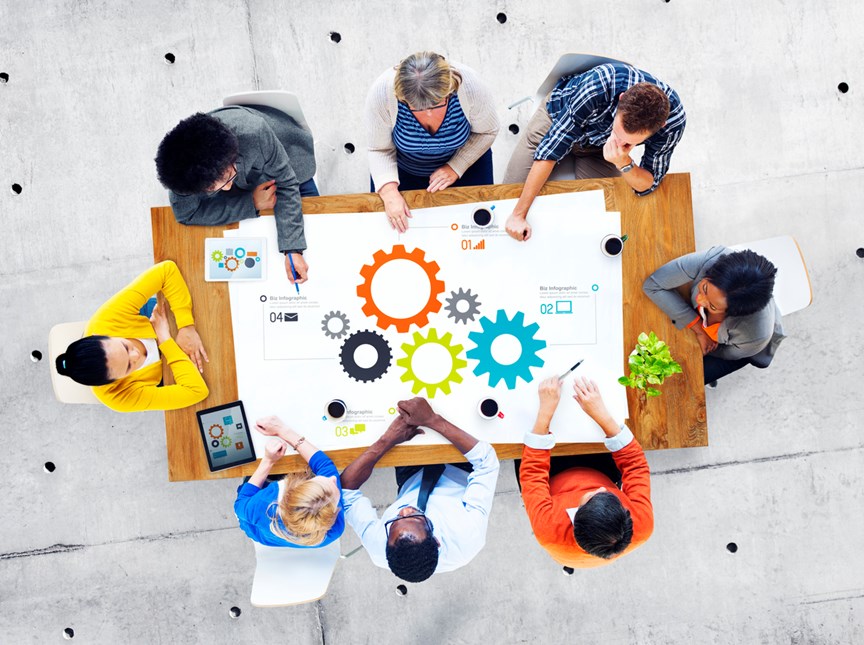 A stock photo of a group of individuals in a meeting sitting around a table