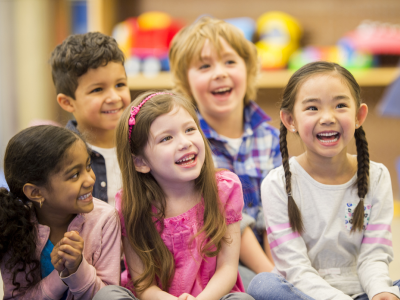 Five seated children looking off screen smiling; link to Lakeland Libraries' Storytime Programs event calendar