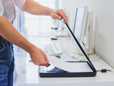 Hands placing paper inside small black scanner