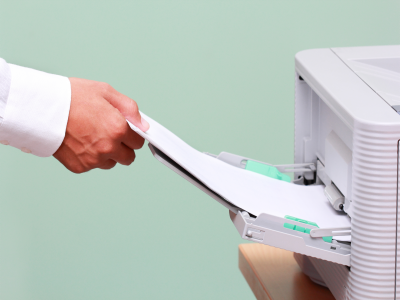 Hand reaching for papers in a printer tray